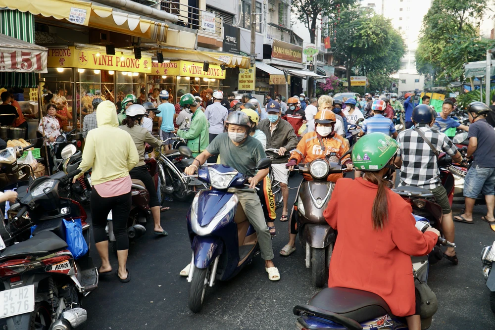 Lượng người đổ về các tiệm vịt quay, heo quay ngày càng đông khiến cả đoạn đường xung quanh ùn tắc, các lực lượng chức năng cũng có mặt để điều tiết giao thông. Ảnh: PHƯƠNG ĐẶNG