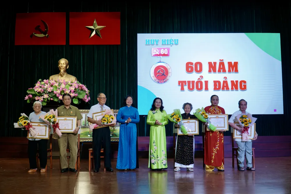 Chủ tịch HĐND TP.HCM Nguyễn Thị Lệ và bà Huỳnh Ngọc Nữ Phương Hồng, Bí thư Quận ủy quận 5 trao tặng huy hiệu Đảng cho 7 đảng viên nhận huy hiệu 60 năm tuổi Đảng. Ảnh: BẢO PHƯƠNG