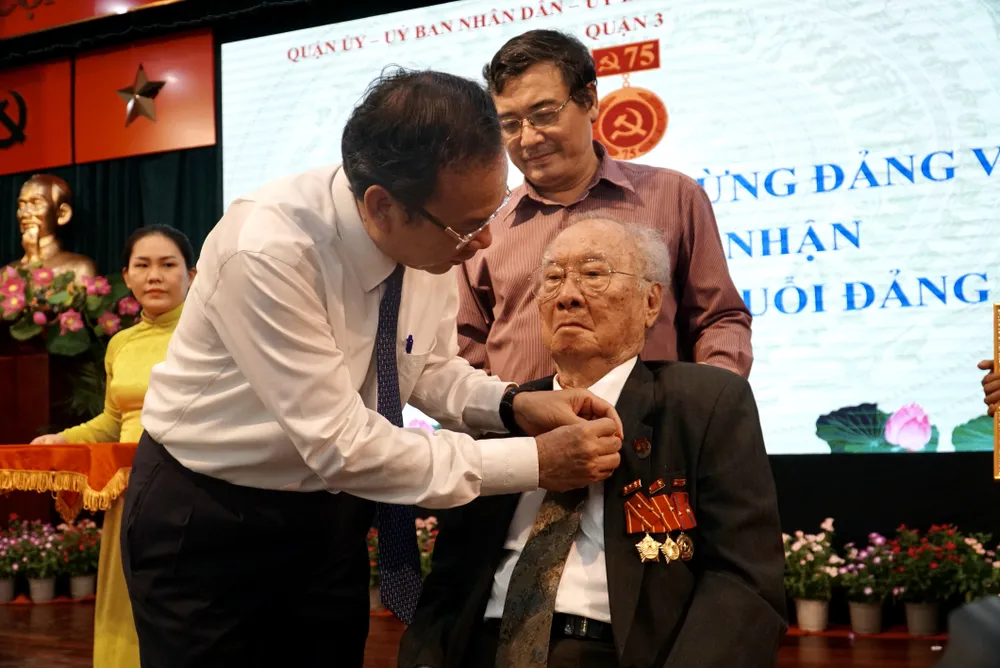 Bí thư Nguyễn Văn Nên trao huy hiệu 75 năm tuổi đảng cho ông Phạm Bá Huy. Ảnh: BẢO PHƯƠNG