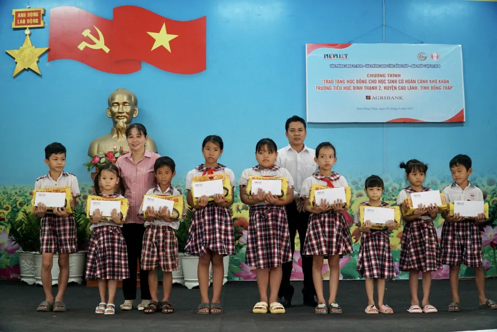 Bà Nguyễn Thị Mai Chi, Chủ tịch UBND xã Bình Thạnh và ông Võ Văn Phương, Phó Giám đốc Agribank chi nhánh huyện Cao Lãnh trao quà hỗ trợ các em học sinh. Ảnh: BẢO PHƯƠNG
