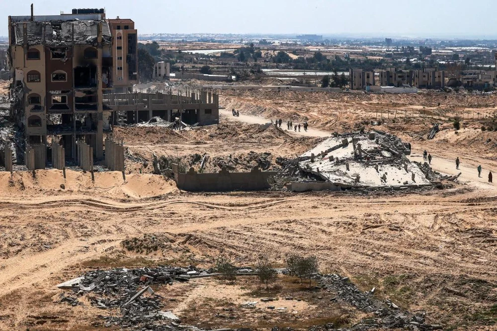Người dân đi qua các tòa nhà bị phá hủy ở TP Khan Younis (nam Gaza) hôm 7-4. Ảnh: AFP tai-thiet-Gaza.webp