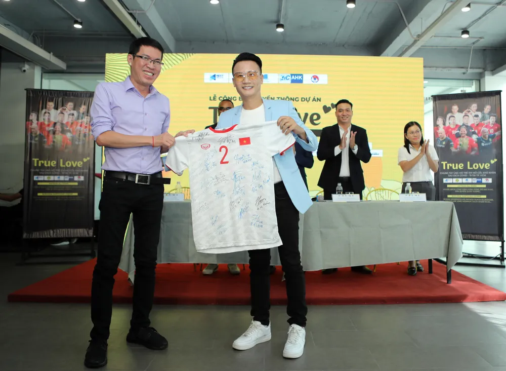 Nhà báo Đỗ Tuấn (báo Bóng đá) trao tặng chiếc áo đấu của trung vệ Duy Mạnh cho ca sỹ Hoàng Bách bán đấu giá trong chiến dịch True Love...