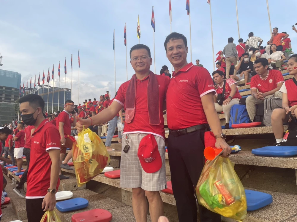 Lê Thanh Hùng (phải) tươi cười sau mấy tiếng đồng hồ kiên nhẫn phụ trách chia vé cho bà con các tỉnh xa ở Campuchia, kiêm chức vụ hậu cần cho nhóm CĐV Việt Nam. Anh Trần Tuấn Ngọc (trái) - phó Tổng Giám đốc Công ty Metfone, người luôn dọn rác sau những trận cầu để nêu cao tinh thần thể thao văn minh trong công ty.