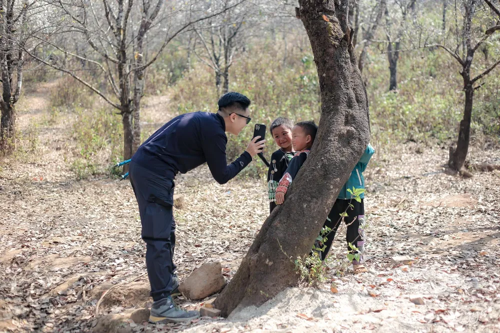 Du khách vui đùa cùng các em dân tộc Mông. Ảnh: LẠC LẠC.