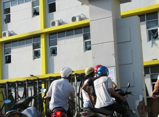 Công nhân Việt Nam Mỹ Thanh đang đọc thông báo. Phía trong là những cửa sổ công bị đập vỡ tan hoang