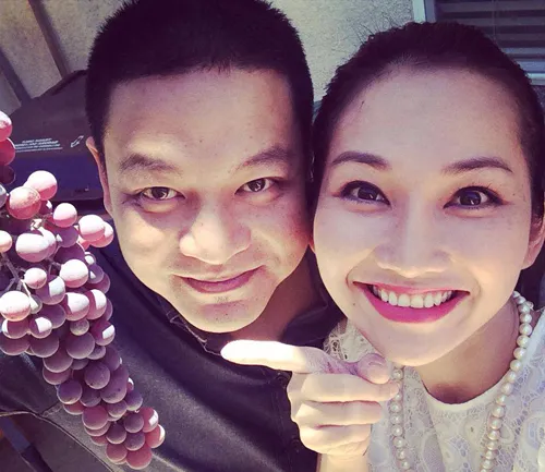 Đôi vợ chồng sắp cười bên chùm nho hái trong vườn nhà Andy ở Mỹ.