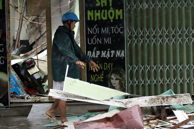 Người này đang dọn lại mái nhà mình bị bão Rammasun đánh tan tác.