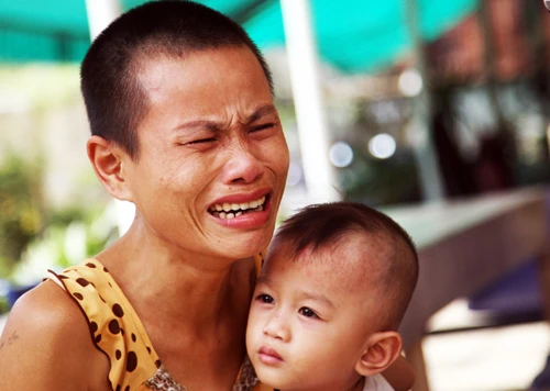 Vợ anh Phước bế con nhỏ khóc ngất trước cái chết tức tưởi của chồng. Ảnh: An Nhơn