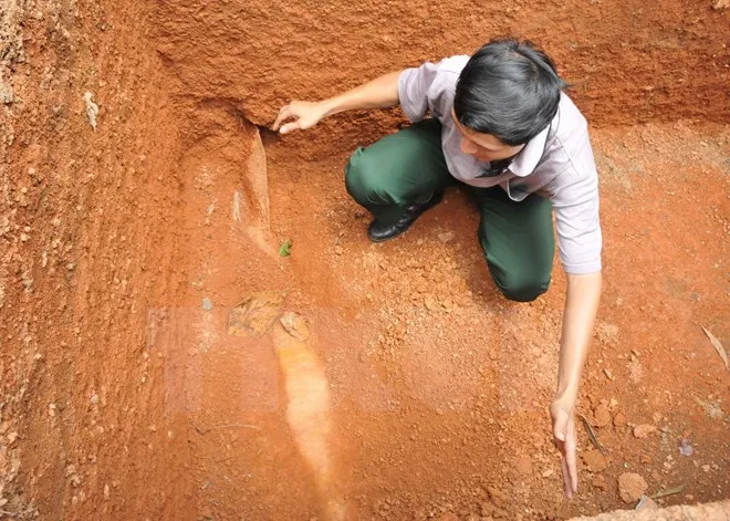 Anh Khoa với quả bom phát hiện khi đào bể xử lý nước thải.(Ảnh: Đậu Tất Thành/TTXVN)