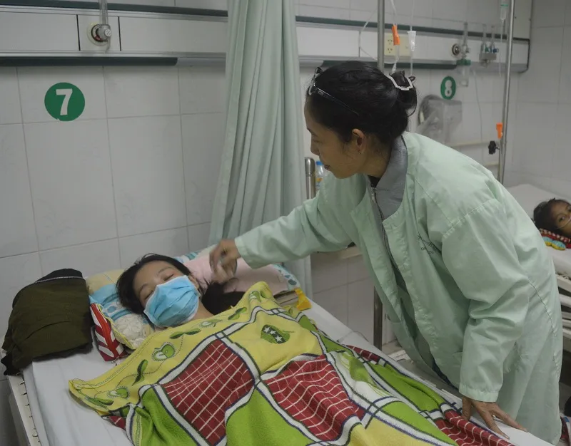 Chị Huỳnh Thị Minh Lam, mẹ của Gia Linh đang chăm sóc cho em khi còn nằm điều trị tại BV. ẢNH: THANH TUYỀN.