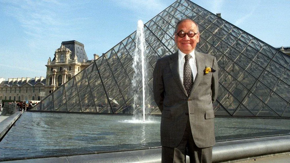IM Pei bên kim tự tháp kính trên sân bảo tàng Louvre.