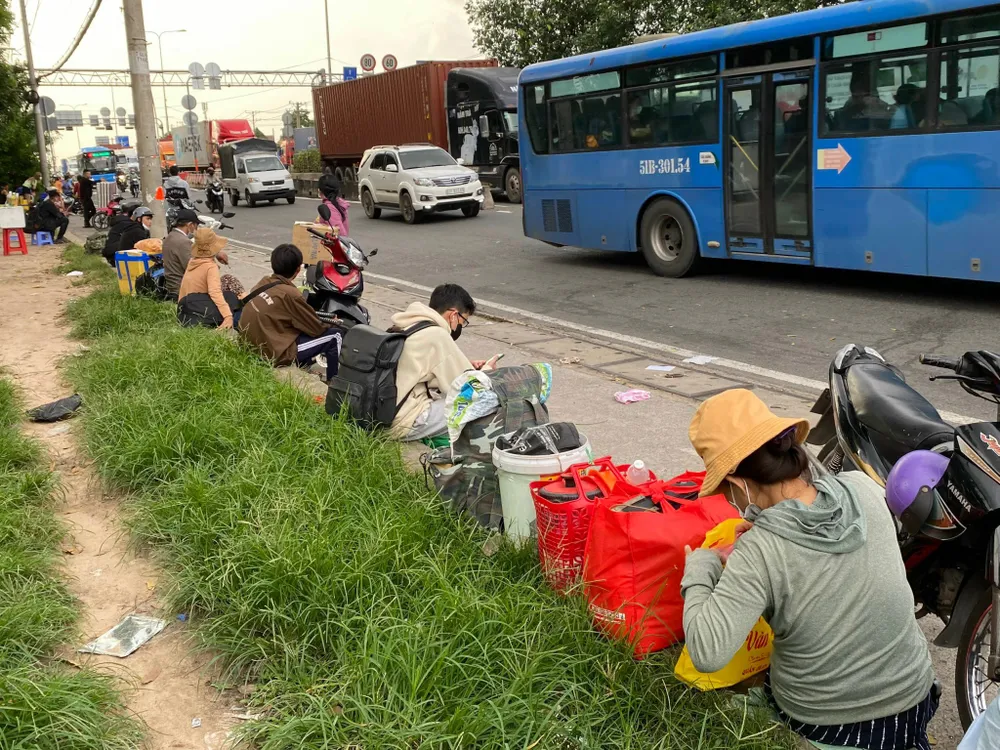 Hành khách ngồi bên vệ đường. ẢNH: CÁT TƯỜNG ben-coc