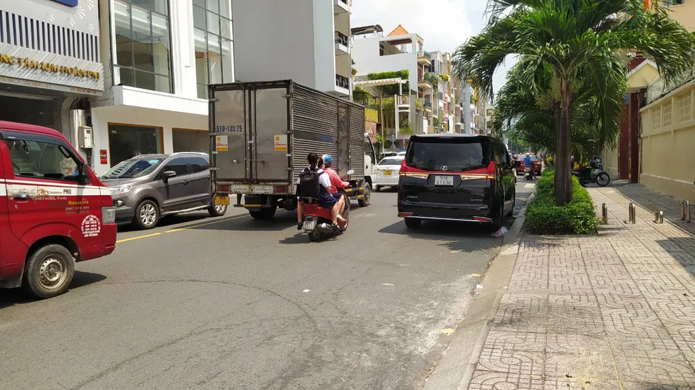 Một phụ huynh chở 2 con không đội mũ bảo hiểm trước khu vực cổng trường THCS Hai Bà Trưng (quận 3). c05e963c0e8fdad1839e.jpg