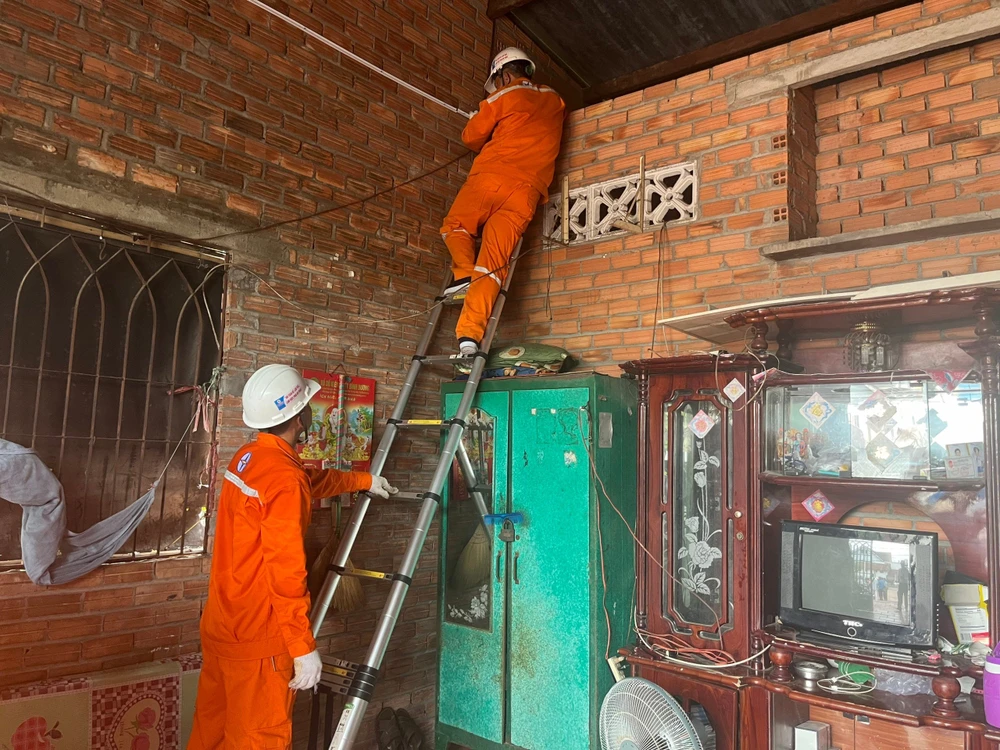 Các công nhân Công ty Điện lực Củ Chi, EVNHCMC đang thay mới và đi lại hệ thống điện cho hộ gia đình ông Nguyễn Văn Trung. EVNHCMC tư vấn khách hàng sử dụng điện an toàn
