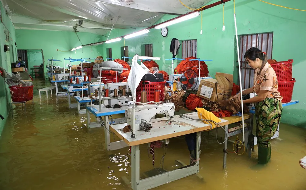 Chủ xưởng may lo lắng trước nguy cơ lũ đổ về máy móc, vải, quần áo bị hư hại. Ảnh: ĐẶNG TRUNG