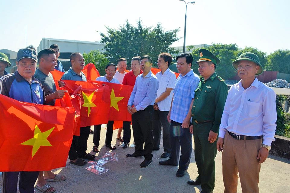 Đại diện các sở ngành liên quan và Báo Người Lao động tặng cờ Tổ quốc cho ngư dân vươn khơi bám biển. Ảnh: Đ.T