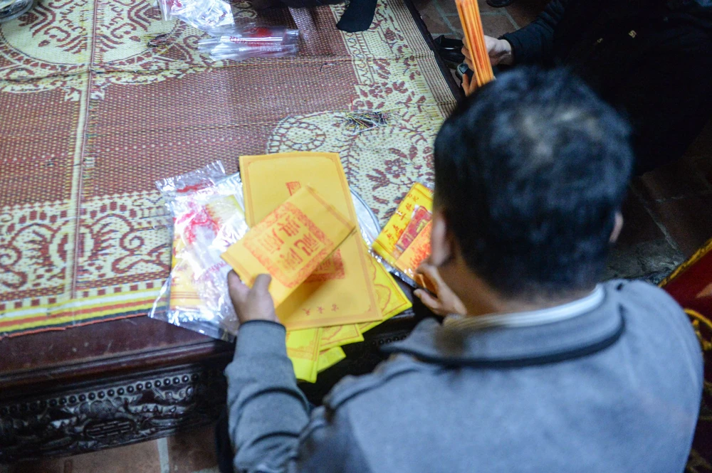 Một người đàn ông sắp xếp lại những lá ấn đền Trần sau khi nhận. Ảnh: ĐT