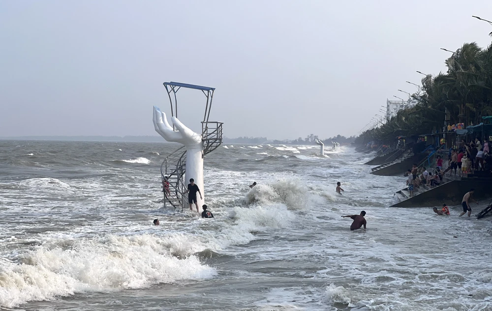 Người dân tắm gần khu vực bàn tay được UBND huyện Hoằng Hóa lý giải là tạo điểm nét mới cho không gian biển Hải Tiến.