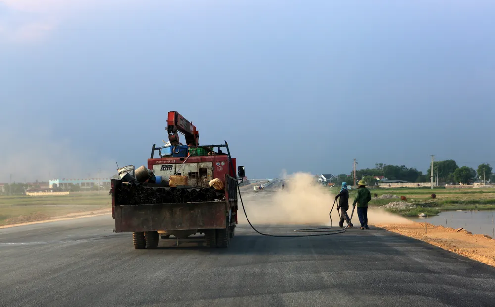 Dưới thời tiết nắng nóng 40 độ C, 2 công nhân vẫn miệt bám công trường, làm sạch mặt đường, cũng như bảo dưỡng sau trải khi thảm nhựa.