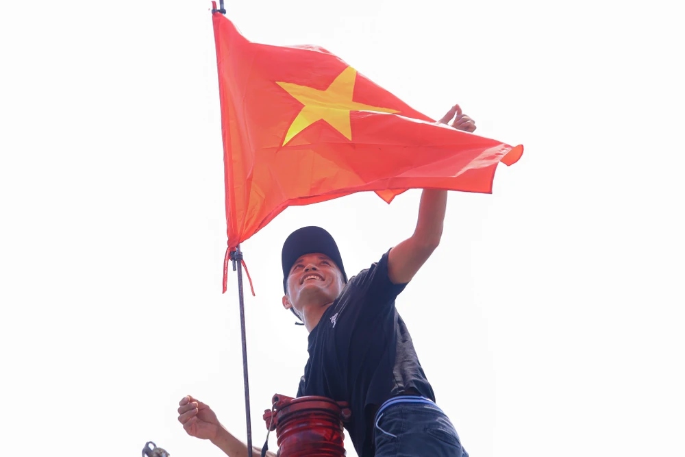 Ngư dân phấn khởi treo lá cờ Tổ quốc vừa được báo Người Lao Động trao tặng. Ảnh: TUẤN MINH