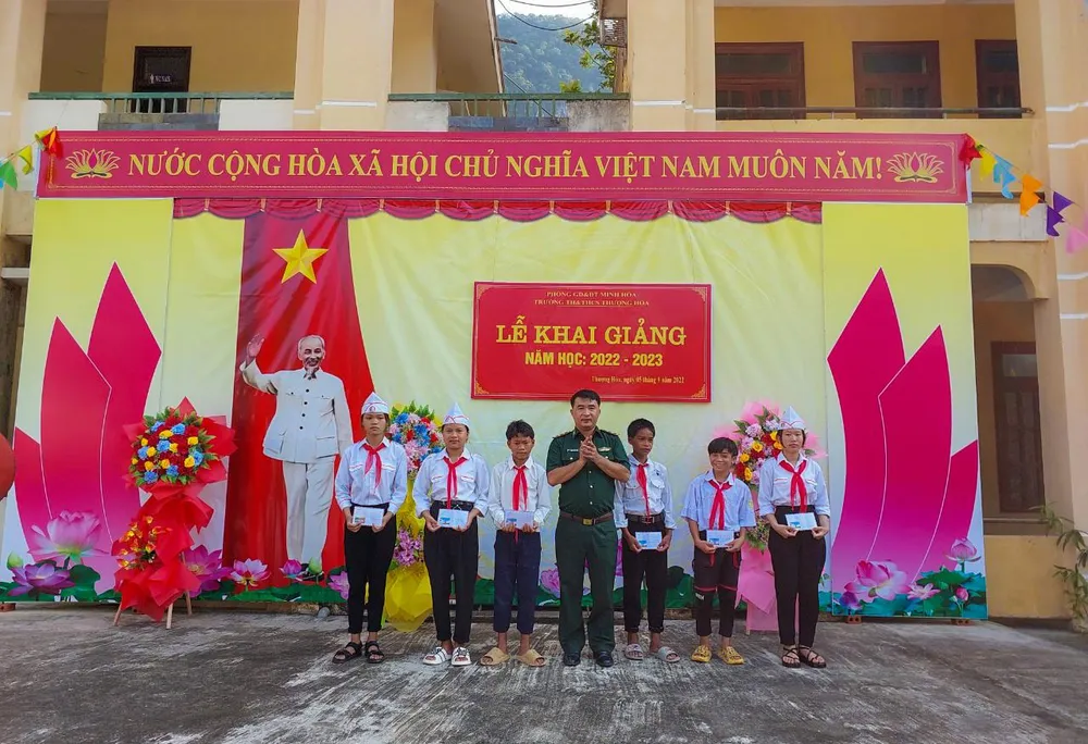 Trung tá Phạm Xuân Ninh, Chính trị viên phó Đồn Biên phòng Cà Xèng trao quà &quot;Nâng bước em đến trường&quot; cho các em học sinh.