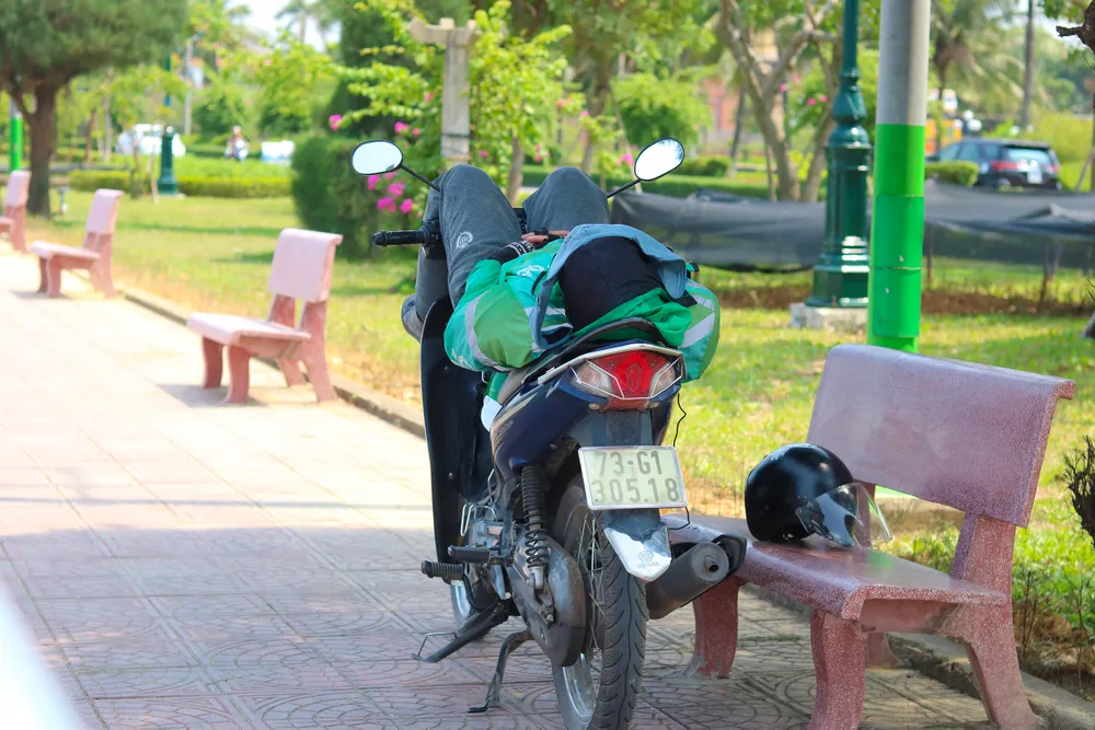 Một tài xế công nghệ chợp mắt giờ trưa trong bóng râm. Ảnh: BẢO THIÊN Một tài xế công nghệ chợp mắt giờ trưa trong bóng râm. Ảnh: BẢO THIÊN