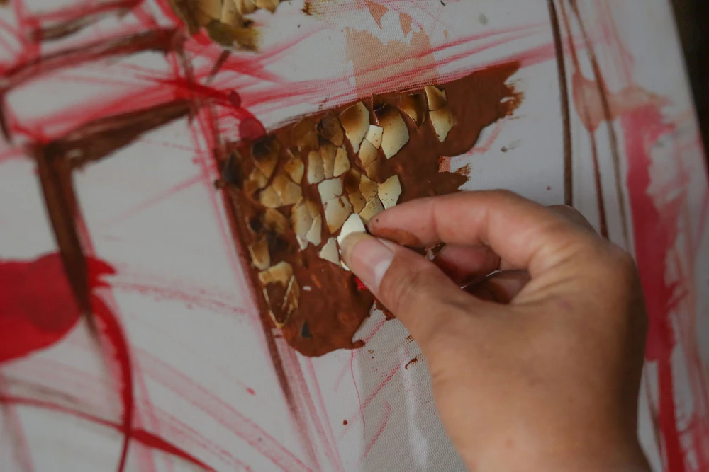 Mỗi công đoạn làm tranh vỏ trứng được họa sĩ Nguyễn Quốc Vượng thực hiện rất tỉ mẩn. Ảnh: B.THIÊN