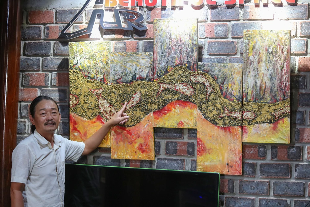Hoạ sĩ Nguyễn Quốc Vượng bên tác phẩm đầu tay “Sông ngầm”. Ảnh: B.THIÊN