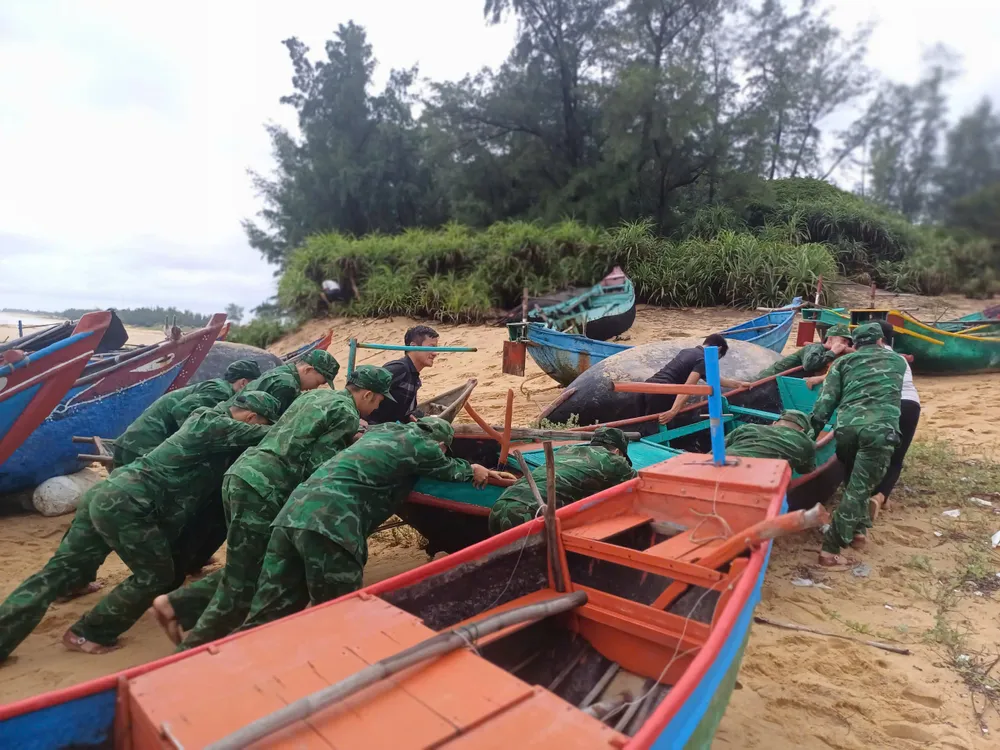 Lực lượng Đồn biên phòng Lý Hòa hỗ trợ người dân đưa tàu thuyền vào bờ tránh bão. Ảnh: B.T z5845203088024_56ab06ce52e7192f517b29bb94a8b5f8.jpg