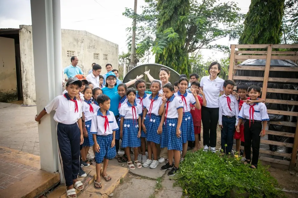 Chị Nguyễn Hồng Hạnh, Cán bộ Nước sạch, Vệ sinh môi trường - UNICEF Việt Nam (áo xanh, bên trái) và cán bộ Masterise Group chia sẻ niềm vui với các em học sinh trường Tiểu học Long Phú C khi đón thiết bị nhà vệ sinh không phát thải. Ảnh: UNICEF Việt Nam\Trương Việt Hùng masterise-3.jpg