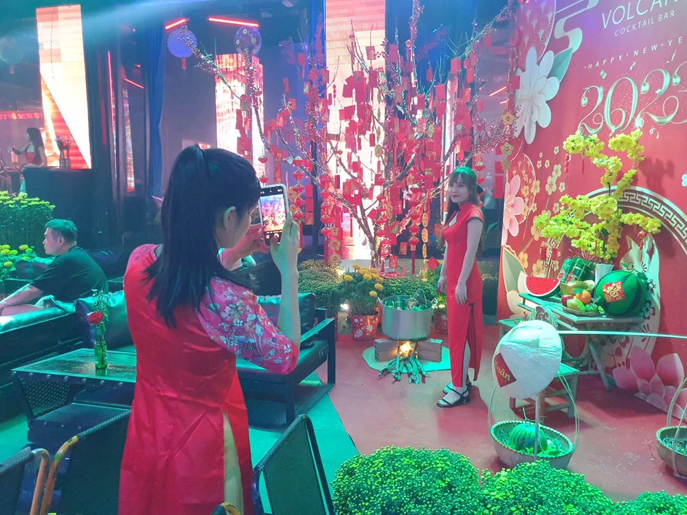 Tranh thủ tạo dáng chụp ảnh trước một quán trang trí theo phong cách truyền thống tết Việt.