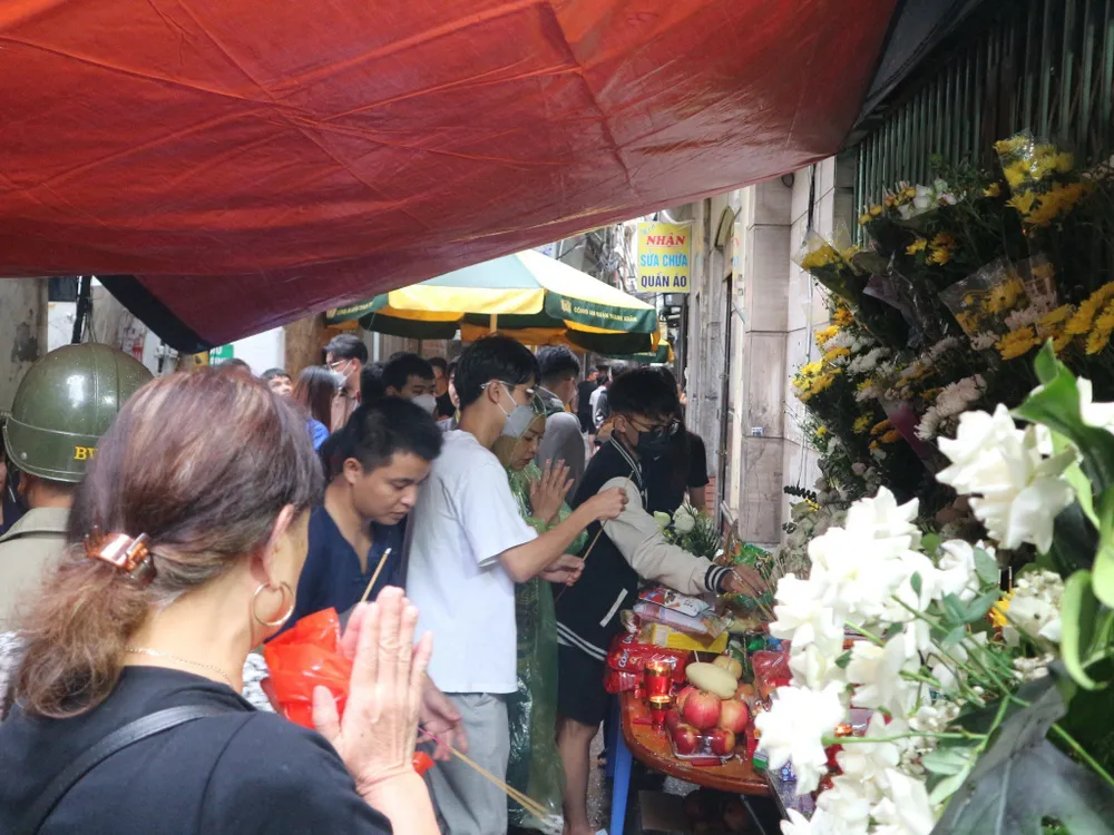 Dù trời mưa lớn, đường sá nhỏ hẹp, khó tìm... nhưng trong con ngõ ấy, lúc nào cũng kín người đến thắp nhang cho những người đã khuất. Ảnh: Thanh Tú người dân thắp hương 2.jpeg