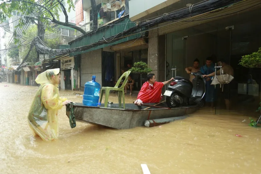 Lực lượng chức năng hỗ trợ người dân di chuyển tài sản lên cao, hạn chế tổn thất do mưa bão, ngập lụt gây ra. Ảnh: PHI HÙNG IMG_0075.JPG
