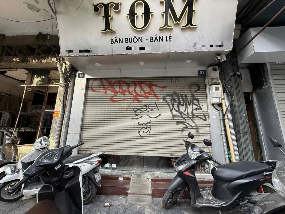 Một cửa hàng quần áo trên phố Hàng Đường (Hà Nội) chỉ mở hé cửa để giao dịch khi có khách. Ảnh: MINH TRÚC cửa hàng đóng cửa 1206 .jpg
