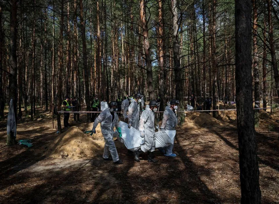 Lực lượng cứu hộ Ukraine khai quật mộ tập thể ở TP Izium, tỉnh Kharkiv ngày 17-9. Ảnh: REUTERS