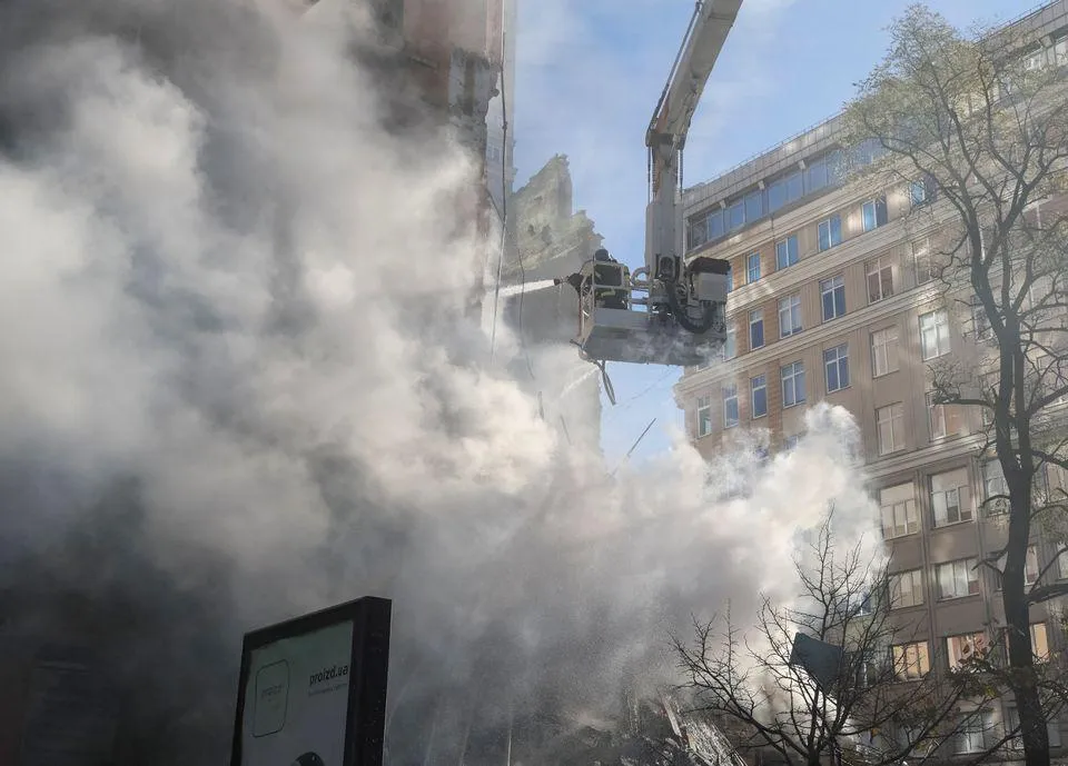 Lính cứu hỏa đang dập lửa tại khu chung cư bị UAV Nga tấn công ở thủ đô Kiev. Ảnh: REUTERS