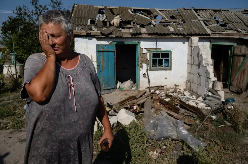 Một người dân đứng trước ngôi nhà bị phá hủy do pháo kích ở tỉnh Kherson vào tháng 8. Ảnh: THE NEW YORK TIMES