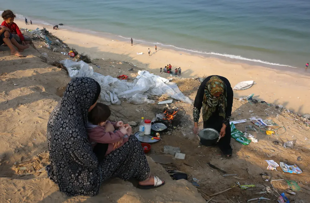 Người dân ở phía bắc Gaza sơ tán về phía nam Gaza đang dùng củi để nấu ăn bên bãi biển vào ngày 28-10. Ảnh: THE NEW YORK TIMES gaza.png