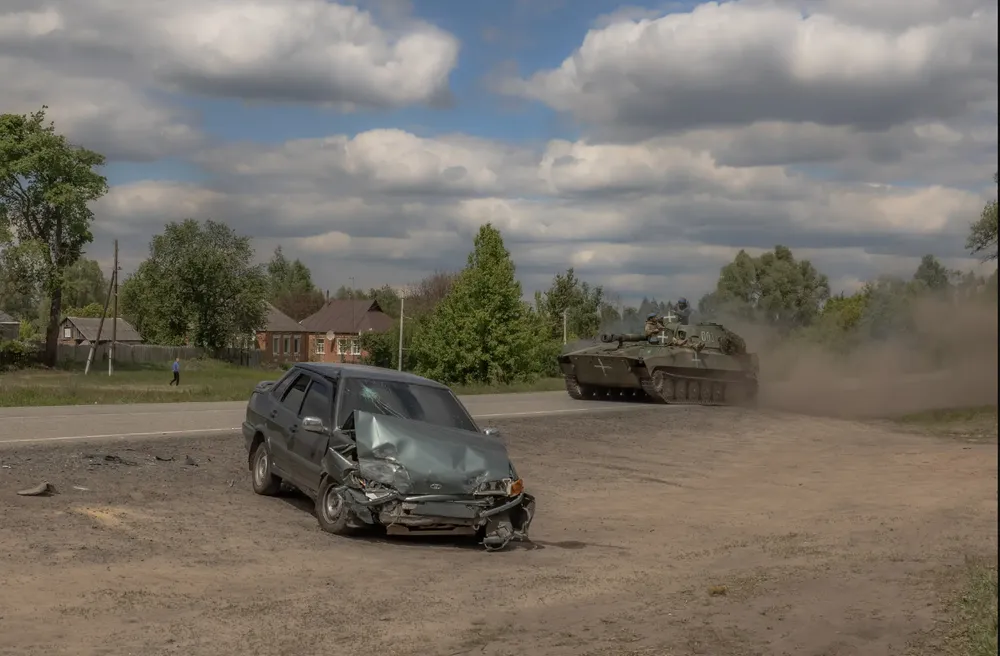 Xe tăng Ukraine gần chiếc xe hơi bị phá hủy do pháo kích tại TP Vovchansk (tỉnh Kharkiv) hôm 12-5. Ảnh: AFP chien-su-nga-ukraine-ngay-14-5.png