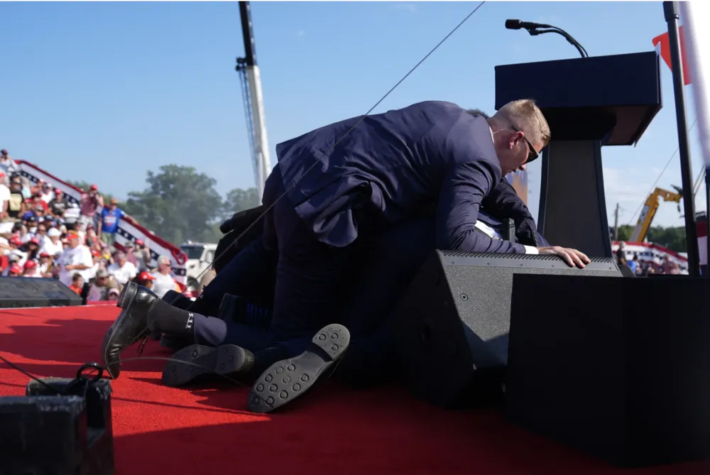 Ông Trump được mật vụ che chắn. Ảnh: AP trump-chay-mau-tai-noi-tranh-cu.png