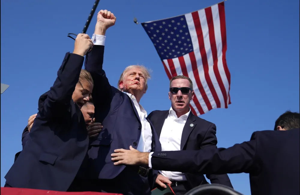 Cựu Tổng thống Donald Trump bị chảy máu và được mật vụ hộ tống khỏi sân khấu tranh cử. Ảnh: AP Cựu Tổng thống Donald Trump bị chảy máu và được mật vụ hộ tống rời khỏi sân khấu tranh cử sau khi có tiếng súng
