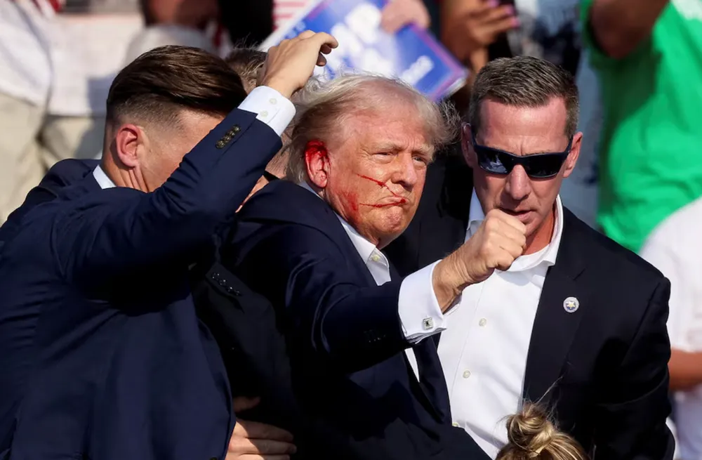 Cựu Tổng thống Donald Trump được mật vụ Mỹ che chắn sau khi ông bị bắn tại sự kiện vận động tranh cử ở TP Butler, bang Pennsylvania (Mỹ) chiều 13-7. Ảnh: REUTERS Ông Trump bị bắn