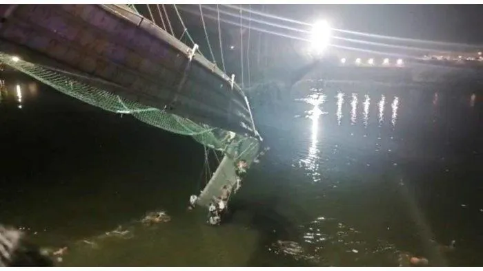 Nhiều người rớt xuống sông Machchu bên dưới khi cây cầu treo ở bang Gujarat, miền tây Ấn Độ bị sập ngày 30-10. Ảnh: REUTERS