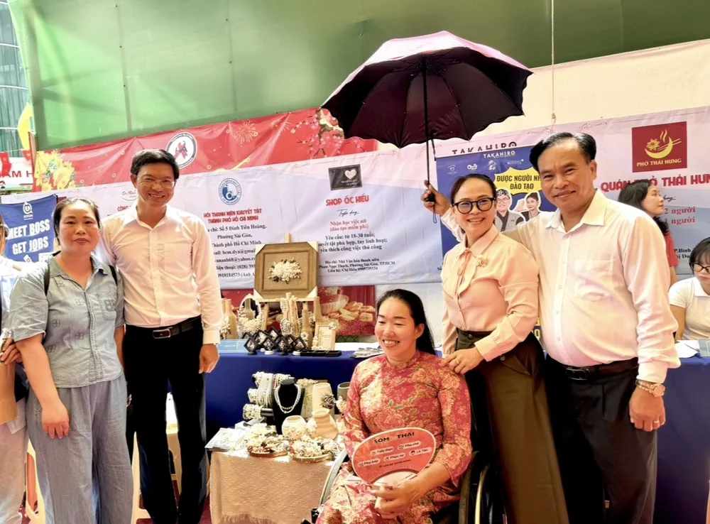 Ông Bùi Thanh Tuấn, Giám đốc Trung tâm Bảo trợ - Dạy nghề và tạo việc làm TP.HCM (thứ 2, từ trái sang) và bà Nguyễn Văn Hạnh Thục, Giám đốc Trung tâm Dịch vụ việc làm TP.HCM (thứ 2, từ phải sang) chụp hình cùng chị Trần Thị Ngọc Hiếu, chủ shop Ốc Hiếu.