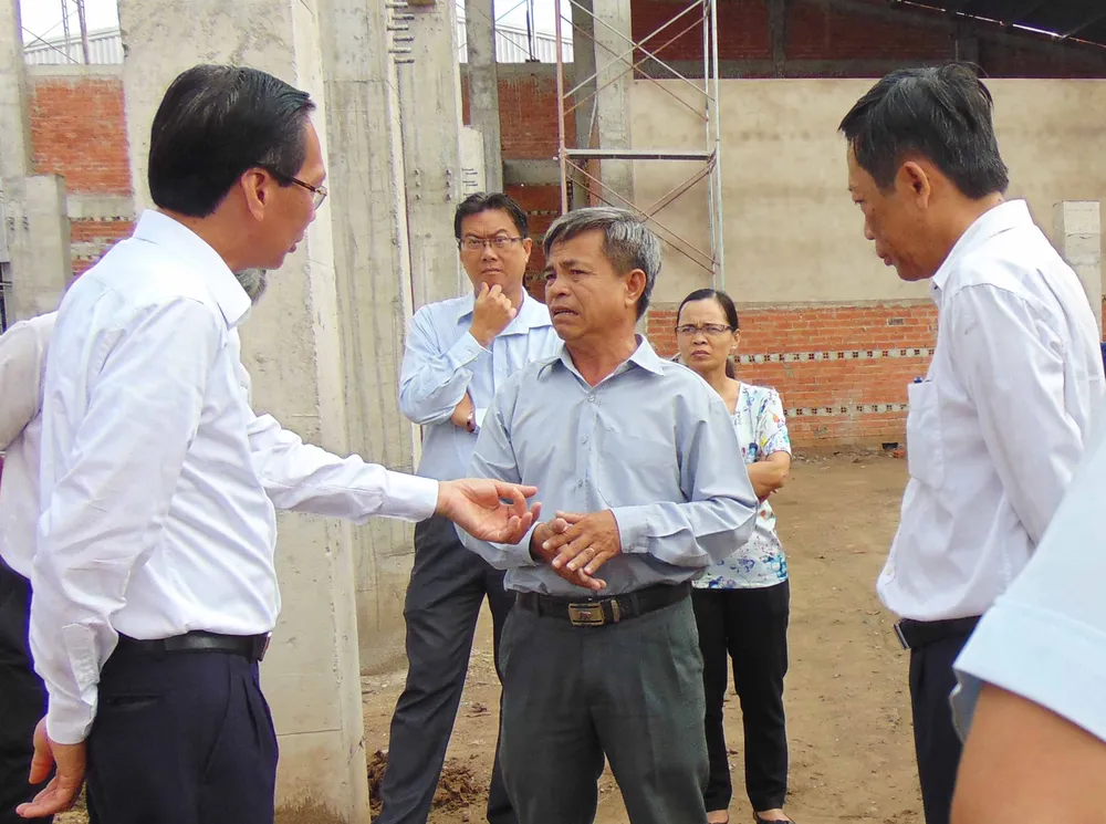 Ông Lê Thanh Liêm (bìa phải) đang trao đổi với đại diện Công ty CP Chế biến thực phẩm Hóc Môn. Ảnh: TRẦN NGỌC