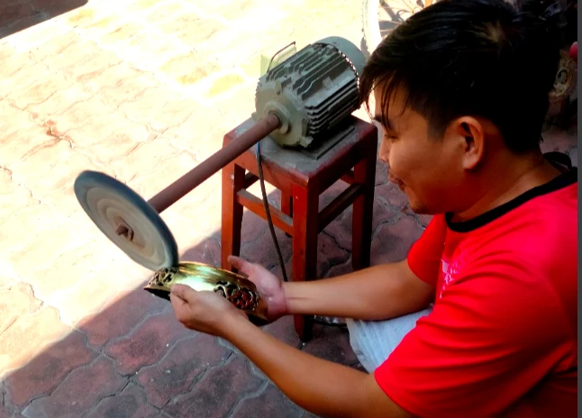Anh Nguyễn Phước Lợi đang tỉ mỉ lau chùi lư đồng của nhà. Ảnh: TRẦN NGỌC