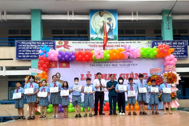 Học sinh có hoàn cảnh khó khăn được tặng quà và thẻ bảo hiểm y tế. Ảnh: TRẦN NGỌC