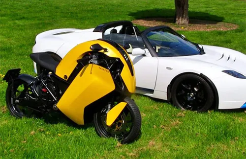 Agility Saietta R màu vàng đứng cạnh ôtô điện Tesla Roadster màu trắng. Cả hai đều thuộc sở hữu của Mark Northwood, một người Anh mê các loại xe điện. agility-saietta-r-8-1378176215.jpg