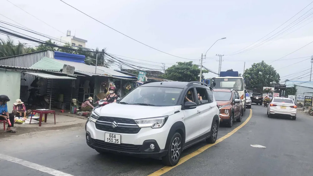 Người dân buôn bán lấn chiếm ra tuyến quốc lộ 62, khiến cho đoạn đường qua cống Rạch Chanh càng khó khăn. Ảnh: DK