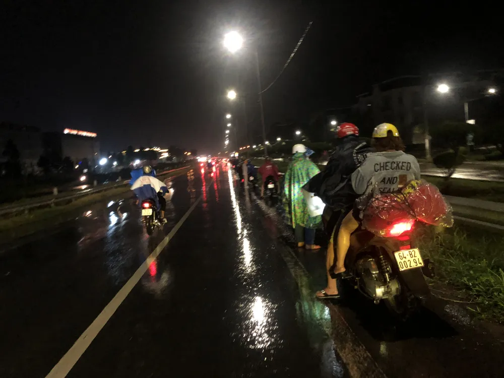 Cơn mưa lớn khiến nhiều người tấp vào ven đường mặc áo mưa để đi tiếp. Ảnh: HUỲNH DU